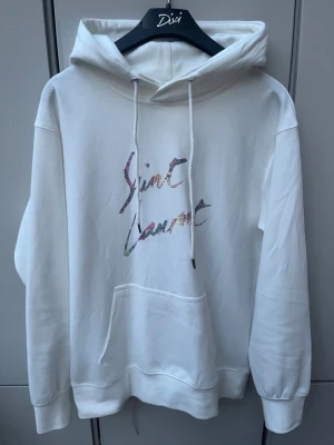 Saint Laurent Hoodie  - Sjukt snygg vit Saint Laurent hoodie i storlek S. Skicket e som ny inga defekter. Kom privat för fler frågor✅