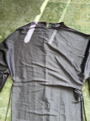 Lila maxiklänning från SHEIN - Säljer en stilren grå långklänning från SHEIN i ett satin material. Klänningen har lång ärm och enkel design med rund halsringning. 