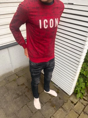 Röd sweatshirt med ICON-tryck - Cool röd sweatshirt med svart mönster och stort vitt 'ICON'-tryck på bröstet. Perfekt för dig  med en trendig streetwear-look.
