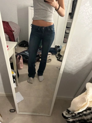 Mörkblå bootcut jeans - Snygga mörkblå vintage bootcut jeans med klassisk femficksdesign och låg midja. Jeansen har en smal passform upptill och lätt utsvängda ben. Perfekta för en avslappnad och trendig look.