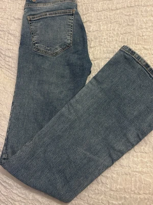 Ljusblå raka jeans med hög midja - Säljer ett par ljusblå jeans med raka ben och hög midja. Klassisk femficksmodell med knapp och dragkedja framtill. Jeansen har en avslappnad passform och är tillverkade i denim. Perfekta för en casual look.