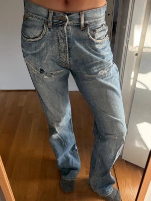 Ljusblå slitna jeans från Jack & Jones - Säljer ett par ljusblå jeans från Jack & Jones med tydliga slitningar och trasiga detaljer på både fram- och baksida. Klassisk femficksmodell med dragkedja och knapp. 
