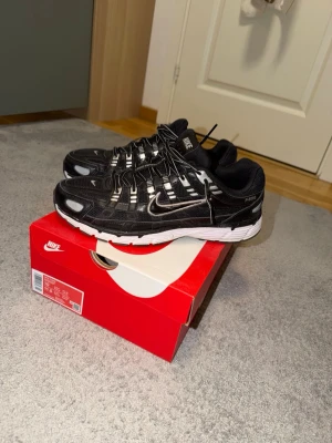 Nike svart-vita sneakers P-6000 - Nike P-6000 sneakers i svart med vita och silvriga detaljer. Skorna har en sportig design med mesh och syntetmaterial, samt en vit och svart sula. Perfekta för dig som gillar streetwear och en clean look.Jag har inte använt de så mycket de är nästan helt fel fria annars jätte sköna och fina skor till alla olika säsonger