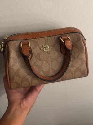 Brun handväska från Coach -  handväska från Coach. Aldrig använt den så den är i helt nytt skick. Finns även band till väskan. 