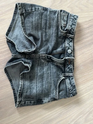 Grå/svarta shorts - Grå/svarta shorts med normalhög midja och knapp, dragkedja och man kan ha skärp!