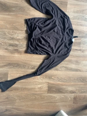Svart långärmad topp - En svart långärmad topp i mjukt och tunt material. Tröjan har en enkel design med rund halsringning och smal passform. Perfekt att styla med jeans eller kjol för en clean look.