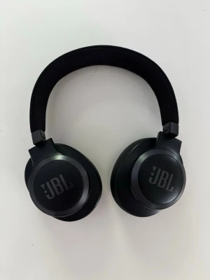 JBL Live 660NC Hörlurar - Snygga svarta over-ear hörlurar från JBL med rundad design och vadderade öronkuddar i konstläder. Bygeln är klädd i tyg för extra komfort och hörlurarna har en stilren, modern look. Perfekta för musik, gaming eller film. Använd fåtal gånger, fungerar perfekt. Väldigt bra noise cancelling ljud!