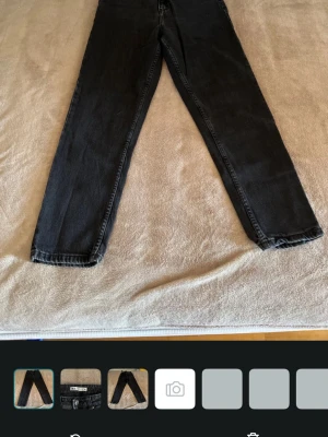 Svarta raka jeans från ZARA - Snygga svarta jeans från ZARA med rak passform och klassisk femficksdesign. Jeansen har bälteshällor och knappgylf. Tillverkade i ett mjukt denimtyg som ger en avslappnad look. Perfekta till en trendig vardagsstil.