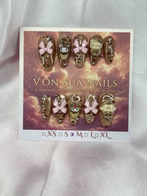 Leomuie (M);Medium Almond - Unika handgjorda press-on naglar i champnage cateye/glittriga underifrån , med leoparddesign samt 3D-dekorationer som rosa rosetter och Sanrio figurer. Naglarna har en medium lång mandel form och är handgjorda för en personlig touch. Perfekt för dig som vill ha något extra till naglarna!M: 16 mm, 12 mm, 12,5 mm, 11,5 mm, 10 mm