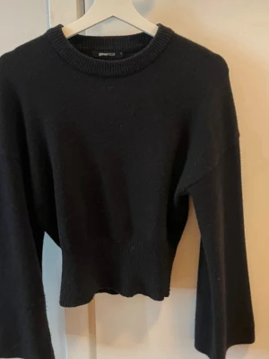 Svart croppad stickad tröja - Säljer en svart croppad stickad tröja från Ginatricot. Tröjan har rund halsringning, bred ribbad mudd i midjan och vid ärmslut samt långa ärmar med avslappnad passform. Perfekt till höst och vinter för en enkel men snygg look.