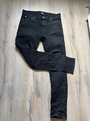 Svarta regular fit jeans - Säljer ett par svarta regular  fit jeans med klassisk femficksdesign och silverfärgade nitar. Jeansen har normal midja och raka ben. Materialet är stretchigt för extra komfort och passform. Perfekta till en avslappnad streetwear-look.