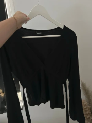 Svart topp - Gina tricot - Snygg svart omlottopp från Gina Tricot med långa ärmar och knytband vid ryggen. As snygg till jeans! Säljer pga för liten💓