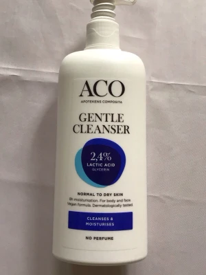 ACO Gentle Cleanser 300ml - Mild rengöring för normal till torr hud från ACO. Innehåller 2,4% mjölksyra och glycerin som återfuktar och rengör både ansikte och kropp. Vegansk formula, parfymfri och dermatologiskt testad. Vit plastflaska med blå och lila detaljer.
