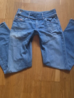 diesel Blå raka/bootcut jeans med låg midja - Säljer ett par klassiska blå jeans med låg midja från diesel. Två knappar Midjemått: 34cm innerbenslängd: 71cm 