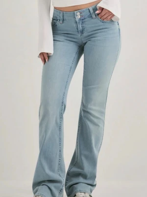 Ljusblå bootcut jeans med brodyr - Säljer ett par ljusblå bootcut jeans med lågmidja och utsvängda ben. Jeansen har klassiska fem fickor och en snygg rosa brodyrdetalj på bakfickan. Tillverkade i mjuk denim med stretch för extra komfort. Slitningar vid hälen.