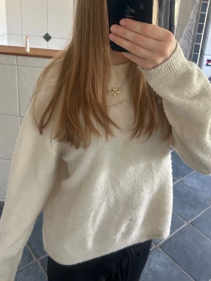 Vit stickad tröja - Mysig vit stickad tröja med rund hals och långa ärmar. Tröjan har ribbstickade muddar vid ärmslut och nederkant, vilket ger en klassisk och enkel look. Perfekt att matcha med jeans eller kjol för en clean stil.