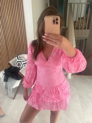 Rosa kort klänning med volang - Supersöt rosa klänning med v-ringning, volangdetaljer och broderade mönster från meet me there. Helt ny och oanvänd och kommer med prislapp. 