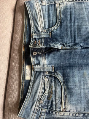 Blå raka jeans från Pepe Jeans - Säljer ett par blå jeans från Pepe Jeans med regular fit, låg midja och raka ben. Jeansen har klassiska fem fickor och snygga kontrastsömmar. Perfekta för en avslappnad och trendig look 💗W28 L32