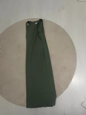 Grön långklänning från Vero Moda - Snygg ribbad långklänning i grönt från Vero Moda AWARE. Klänningen har en ärmlös design och är tillverkad i ett mjukt, stretchigt material som sitter bekvämt. Perfekt för dig som gillar enkel och stilren look.
