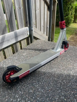 Trick sparkcykel NKD silver/röd - Säljer en stilren trick sparkcykel från NKD i silver med röda detaljer och svarta handtag. Scootern har robust aluminiumram, röda metallhjul och greppvänligt styre. Perfekt för skateparken eller att cruisa runt med. #scooterlife