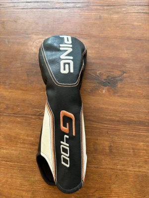 PING G400 headcover svart/vit - Säljer ett headcover till golfklubba från PING, modell G400. Fodralet är svart med vita och kopparfärgade detaljer samt broderad logga. Tillverkat i konstläder och passar perfekt för att skydda din driver eller träklubba.