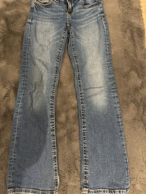 Blå bootcut jeans  - Säljer ett par blå bootcut jeans. Jeansen har ljus tvätt och kontrastsömmar. Perfekta för en avslappnad och trendig look. Materialet är denim i bomull.