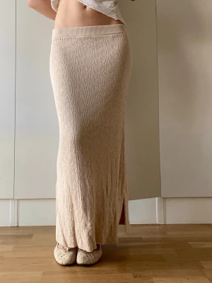 Ny beige långkjol med slits - Säljer en beige långkjol i ett mjukt, ribbat material. Går långt ner på mig som är 176cm och passar flesta storlekar då det är stretchigt skönt material. Perfekt till sommaren och helt ny med prislapp, ordinariepris 849kr. 