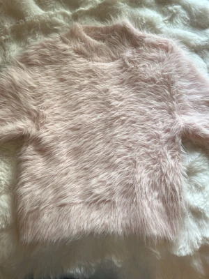 Ljusrosa fluffig stickad tröja - Supersöt ljusrosa stickad tröja från Carin Wester i storlek XS. Tröjan har en fluffig, lurvig yta och rund halsringning. Perfekt för dig som vill ha en mysig och trendig look. Materialet känns mjukt och fluffigt. Köptes för 500kr och har använts ett fåtal gånger 