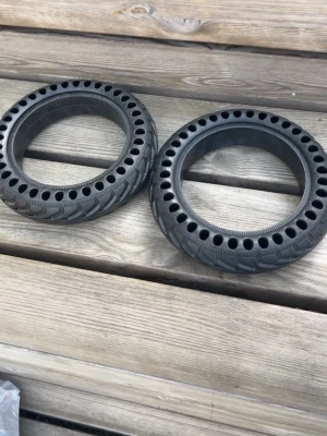 Svarta massiva däck till elscooter - Två svarta massiva däck till elscooter med ventilationshål runt om. Däcken är tillverkade i slitstarkt gummi och har ett mönster för bra grepp. Perfekt för dig som vill slippa punktering och underhåll.