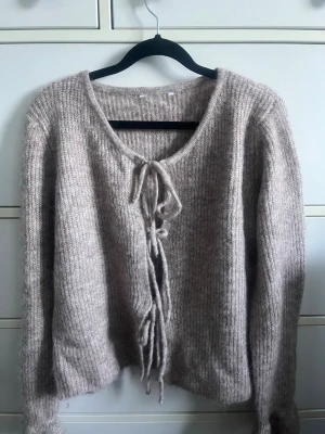 Beige stickad tröja med knytning - Mysig beige stickad tröja med ribbad struktur och knytning framtill. Den är köpt utomlands så har tyvärr inget märke! Perfekt inför hösten ❣️