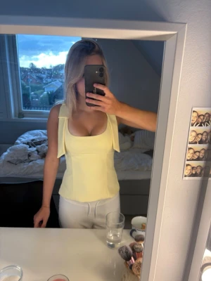 Ljusgul ärmlös linnetopp - Snygg ljusgul linnetopp med breda axelband och fyrkantig urringning. Toppen sitter mycket bra och är i storlek XS