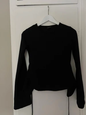 Svart långärmad topp med snörning - En svart långärmad topp med snörning med öppen rygg som är knytbar, säljer på grund av att den blivit förliten💗