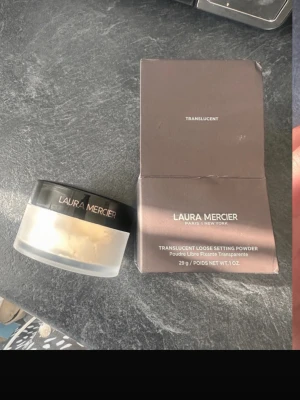 Laura Mercier Translucent Loose Powder - Translucent Loose Setting Powder från Laura Mercier i färgen translucent. Kommer i en rund burk med svart lock och tillhörande kartong. Pudret är lätt och transparent, perfekt för att fixera foundation och ge en matt finish. Innehåller 29g.