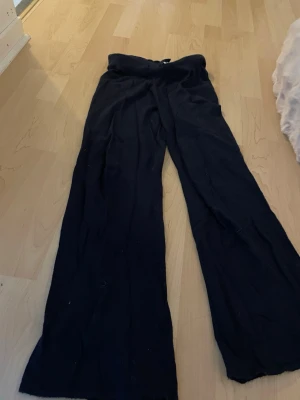 Mörkblå vida mjukisbyxor - Mörkblå mjukisbyxor med breda ben och hög midja. Byxorna har en avslappnad passform och är tillverkade i ett mjukt och bekvämt material, perfekta för en chill stil. Dragsko i midjan för justerbar passform.
