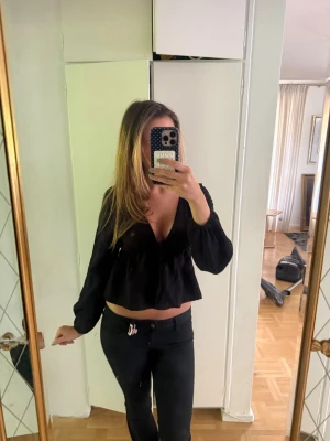 Svart croppad blus med v-ringning - Säljer en svart croppad blus med djup v-ringning och långa ärmar. Storlek M men passar S