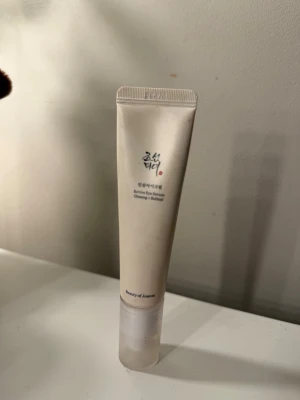 Revive Eye Serum från Beauty of Joseon - Revive Eye Serum från Beauty of Joseon i en smidig tub. Produkten är ljusbeige och har svart text med asiatiska tecken. Innehåller ginseng och retinol, perfekt för ögonområdet. Tuben är av plast och har en minimalistisk design.