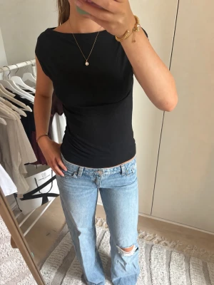 Svart tight topp med kort ärm - En enkel och stilren svart topp med tight passform och korta ärmar. Toppen har en rund halsringning och är gjord i ett mjukt, stretchigt material som sitter snyggt på kroppen. Perfekt att matcha med jeans eller kjol för en clean look.