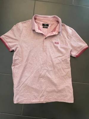 Hugo Boss pikétröja - Säljer en rosa pikétröja från Hugo Boss . Tröjan har ett snyggt och diskret mönster, och broderad Hugo Boss logga på bröstet. | Regular fit, sitter extremt bra. | Storlek: M, men sitter som en S. | Endaste använd ett fåtal gånger så i väldigt bra skicka. | Vid frågor om produkten eller priset är de bara att höra av sig! // William