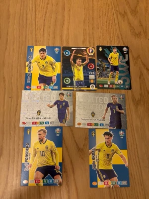 Svenska landslaget fotbollssamlarbilder - Samling med sju fotbollssamlarbilder från svenska landslaget, med spelare i gula och blå matchställ. Korten har färgstarka designer och visar spelare som Emil Forsberg, Sebastian Larsson och Victor Nilsson Lindelöf. Perfekt för dig som gillar fotboll och samlarbilder. 