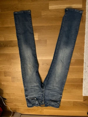 Blå slim fit jeans från Jack & Jones - Säljer ett par blå slim fit jeans från Jack & Jones. Jeansen har klassisk femficksdesign, dragkedjegylf och snygga slitningar på låren för en trendig look. Perfekta till vardags och passar till det mesta i garderoben. L30 W27
