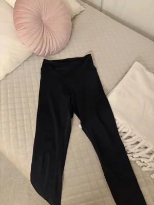 Svarta höga midjeleggings - Säljer ett par svarta leggings med hög midja och stretchigt material. De har en enkel och stilren design utan synliga loggor eller detaljer. Perfekta för en avslappnad look eller till träning. Passar dig som gillar bekväma och smidiga plagg.
