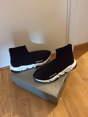 BNCIGA Speed Trainer svarta sneakers - Svarta Speed Trainer sneakers med vit chunky sula och stickad ovandel i stretchigt tyg. Strumpmodell med högt skaft och diskret logga på sidan. Modern och sportig design som sticker ut.