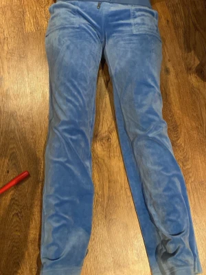 Riktiga Juicy byxor. Vi vek ner dom - Säljer ett par blå mjukisbyxor i mjuk velour med raka ben och fickor både fram och bak. Byxorna har resår i midjan och en avslappnad passform som är perfekt för chill dagar. Snyggt retro vibe och superbekväma! Lite slittna nere vid hälen