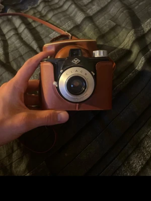 Agfa Clack kamera med läderväska - Säljer en retro Agfa Clack kamera i svart och silver med tillhörande brun läderväska. Kameran har en klassisk design med rund lins och tydliga detaljer. Perfekt för dig som gillar vintageprylar och analog foto. Kameran är Otestad 
