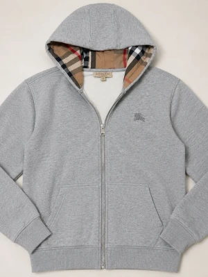 Burberry Zip Hoodie - Snygg grå hoodie med dragkedja från Burberry. Huvan har det klassiska rutmönstret på insidan och tröjan har två fickor framtill. Tillverkad i mjuk bomullsblandning och har ribbade muddar vid ärmar och nederkant. Perfekt för en chill och stilren look.