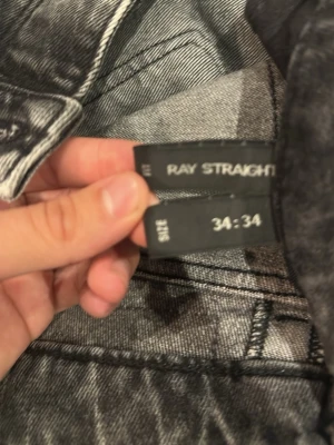 Grå raka jeans Ray Straight 34/34 - Säljer ett par grå raka jeans i modellen Ray Straight. Jeansen har klassisk femficksdesign, normal midja och raka ben. Snygg tvättad grå färg som passar till det mesta. Perfekta för dig som gillar en avslappnad men stilren look.