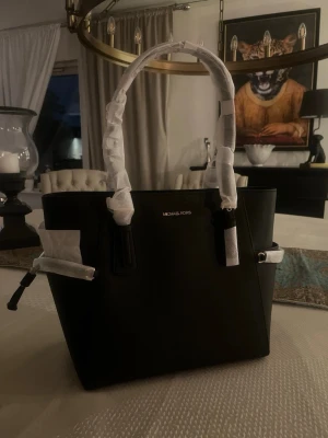 Svart handväska från Michael Kors - Svart handväska från Michael Kors. Som man ser på bilder är den helt ny och aldrig använd. Vill man vill ha mer bilder så är det bara att skriva. 