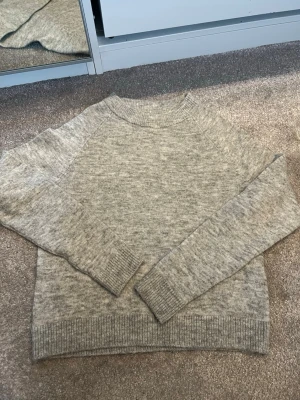 stickad tröja - Mysig ljusgrå stickad tröja från Vero Moda med rund halsringning och ribbade muddar vid ärmslut och nederkant. Perfekt för lager på lager och enkel att matcha till olika outfits. Klassisk och stilren modell i mjukt material.
