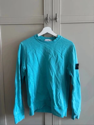 Stone island tröja  - Stone Island Sweatshirt – Ljusblå  Stilren ljusblå Stone Island-tröja med den ikoniska Stone Island-badgen på ärmen. En clean och exklusiv modell som är lätt att matcha och fungerar perfekt till både vardag och streetwear.  • Ljusblå • Stone Island • Klassisk badge på ärmen • Storlek: S • Skick: mycket bra  Skickas fort!