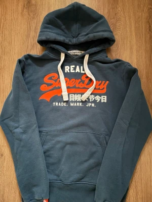 Superdry hoodie  - Snygg mörkblå Superdry hoodie med orange tryck och tjocka snygga snören. Bra skick👍. Storlek S.        Skriv om ni har några funderingar!😃